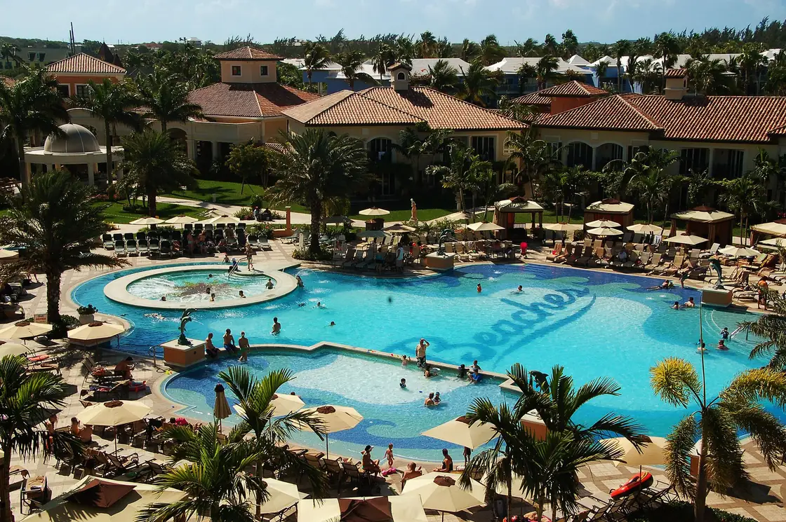 A pool at Beaches Turks and Caicos, with palm trees and the resort buildings behind it